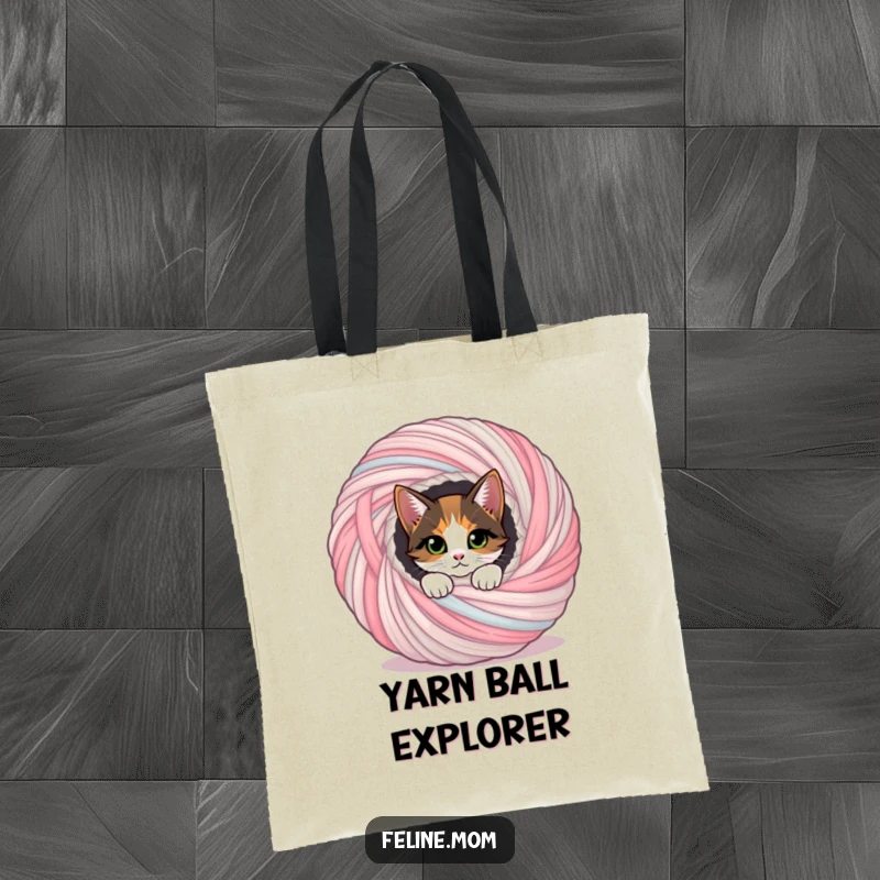Funny calico cat peeking out of a large yarn ball, a stylish tote and funny gift.